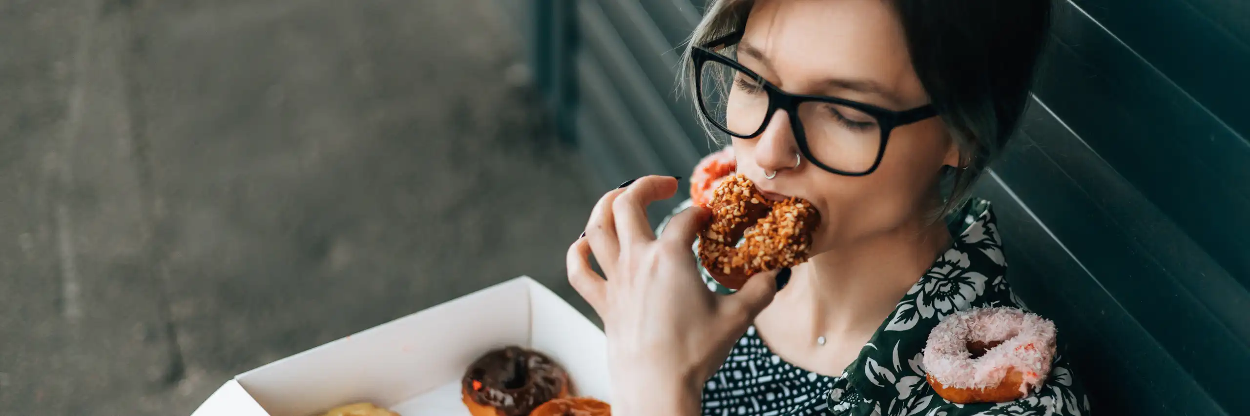 Une jeune femme mange une boite de donuts.