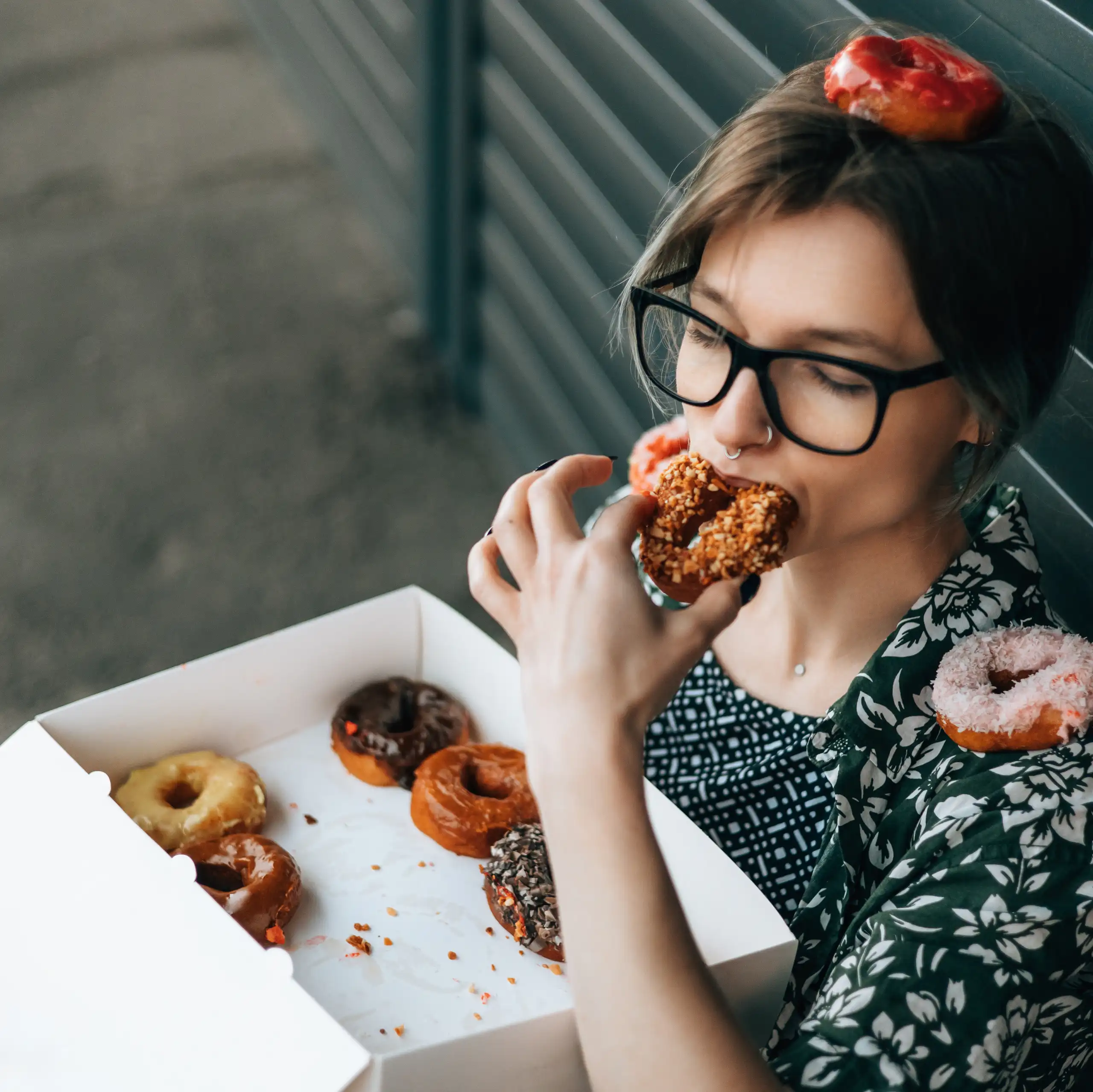 Une jeune femme mange une boite de donuts.