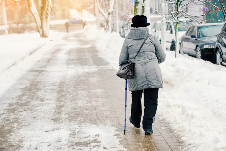 An elderly person walking on an icy path.