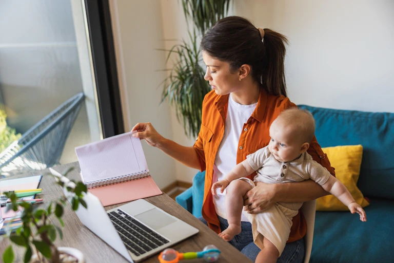 Une femme travaille à son bureau tout en s'occupant de son bébé.