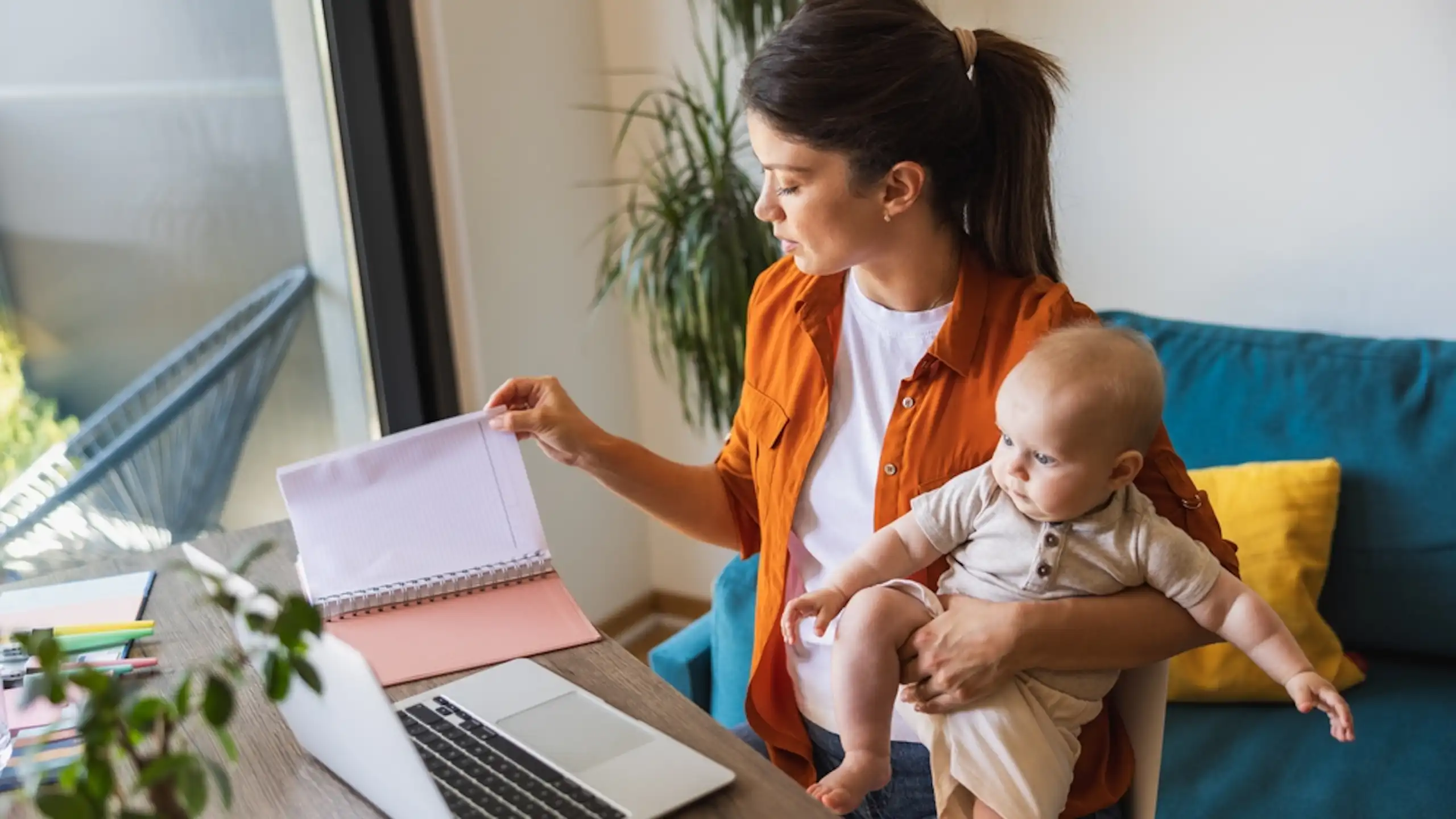 Une femme travaille à son bureau tout en s'occupant de son bébé.