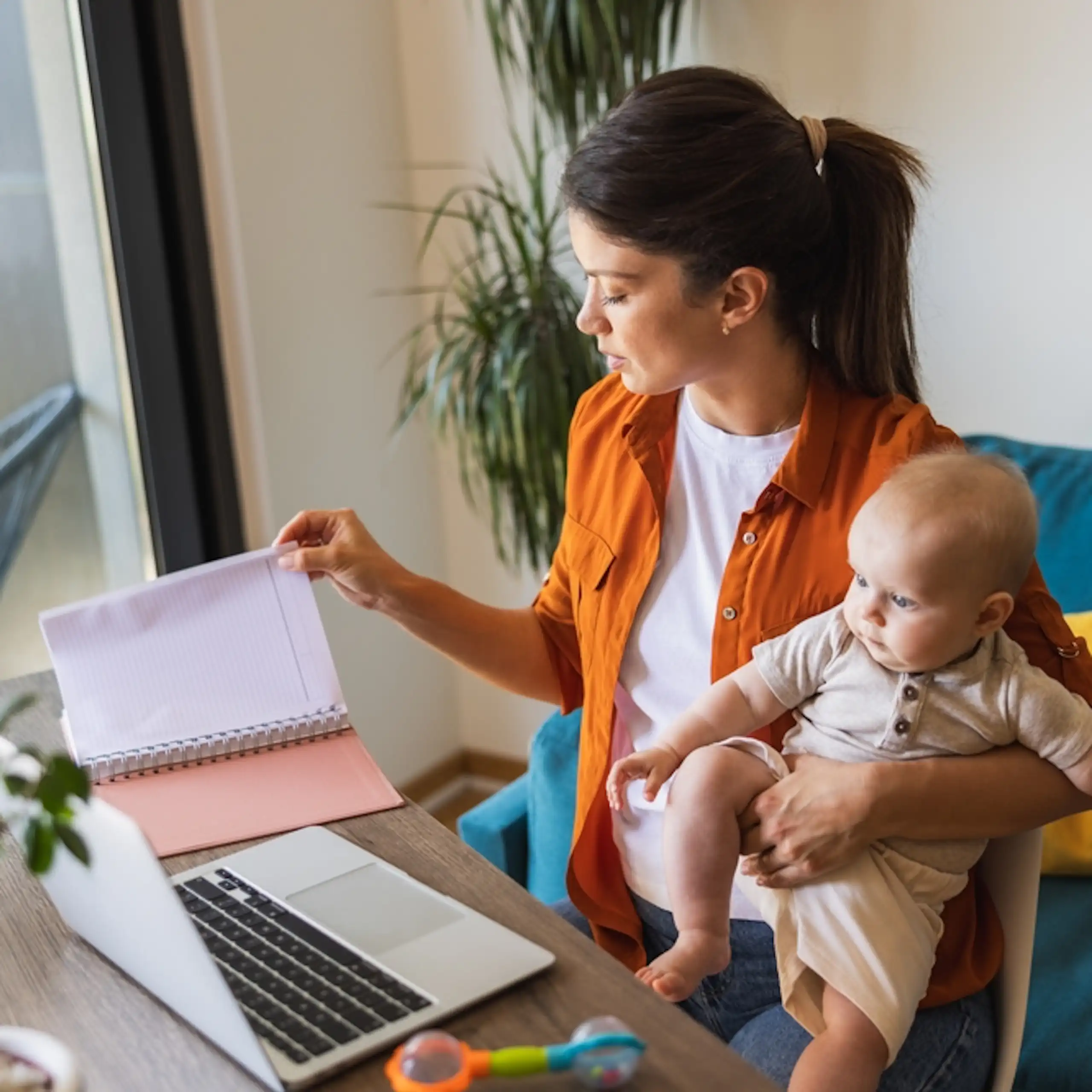 Une femme travaille à son bureau tout en s'occupant de son bébé.