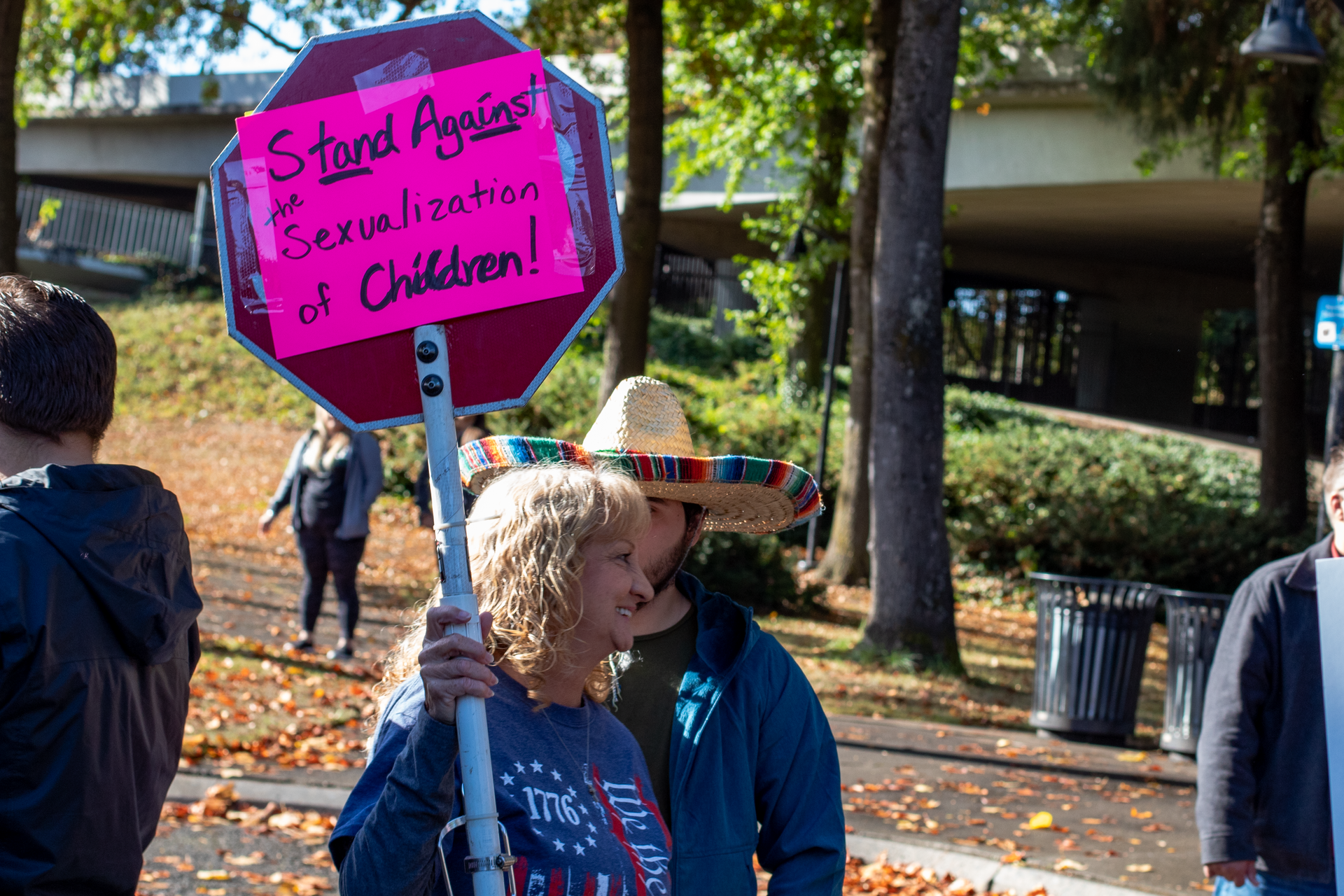 Une femme tient une affiche en protestation contre l'initiative « Drag Queen Story Hour »
