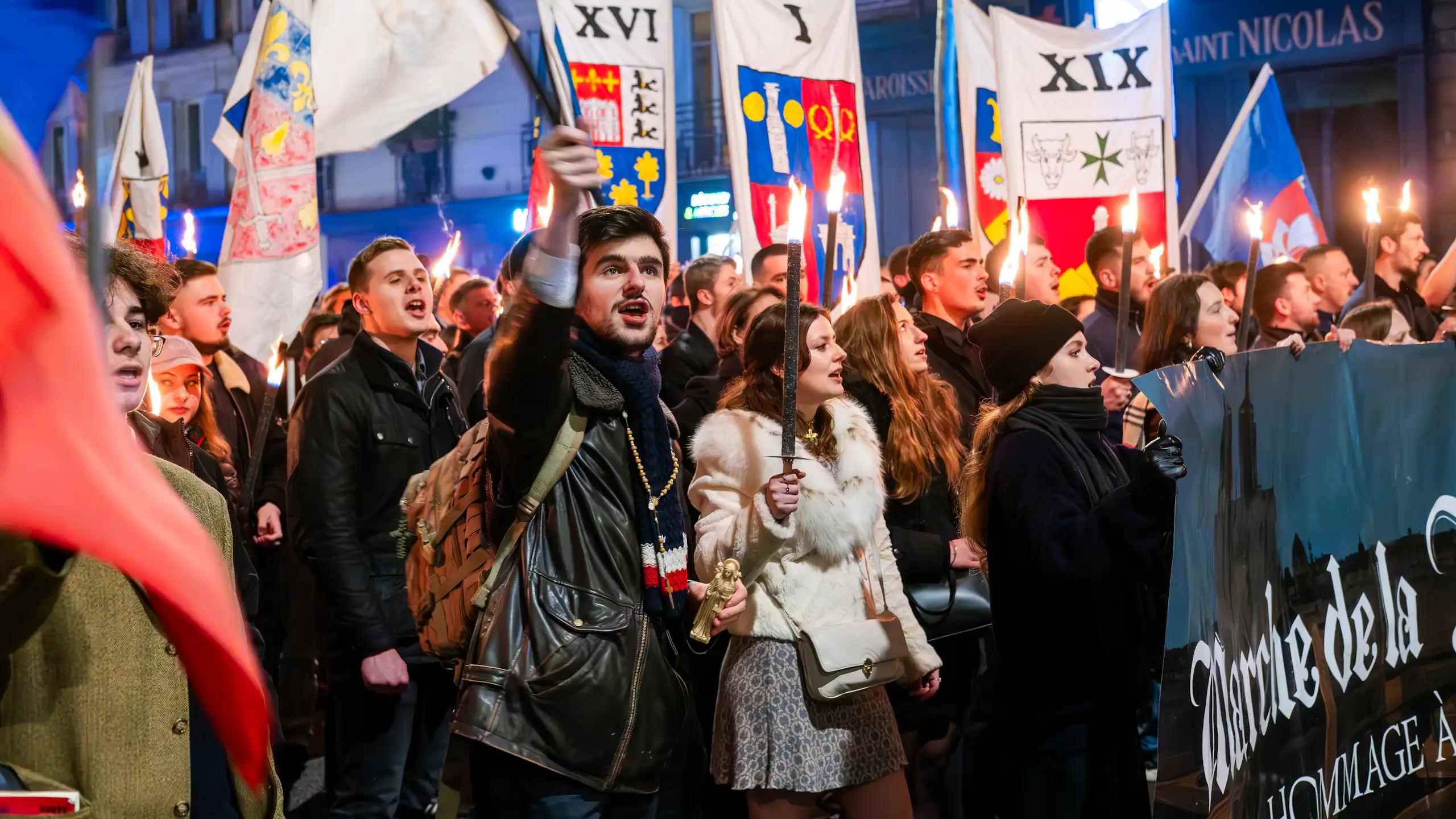 Young people carrying flags and torches marching down a street