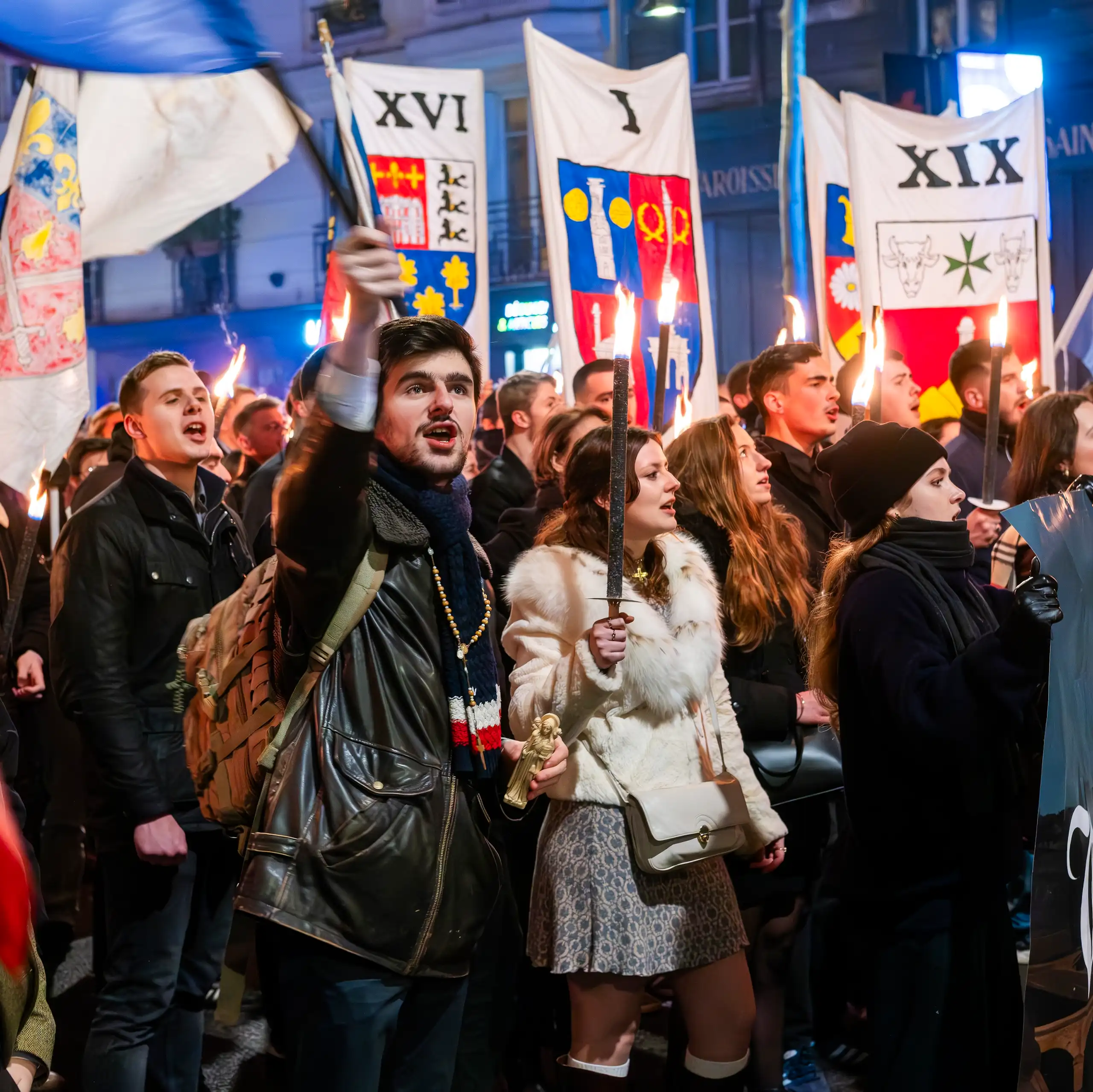 Young people carrying flags and torches marching down a street