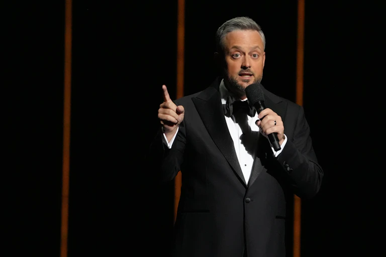 A man in a tuxedo holding a microphone.