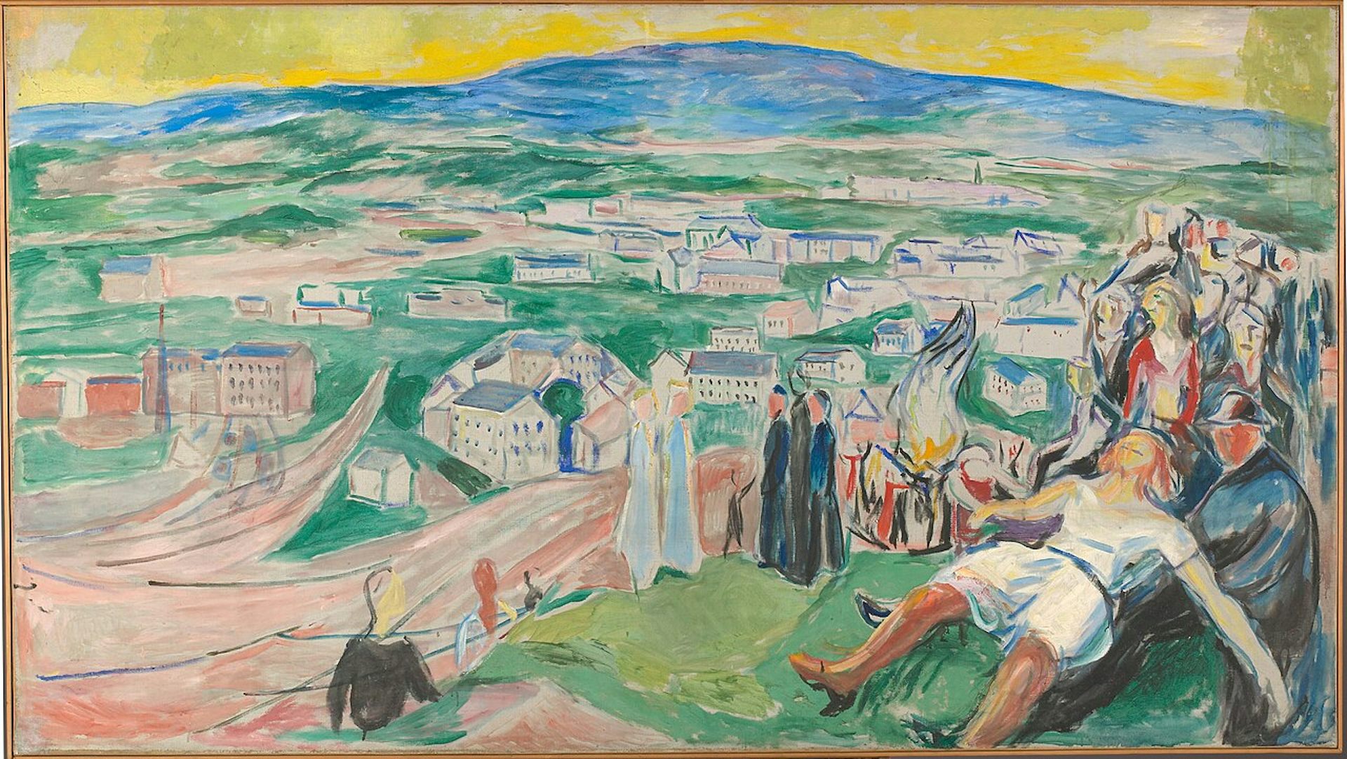 A picture of people celebrating the night of San Juan on a hill near a small town.