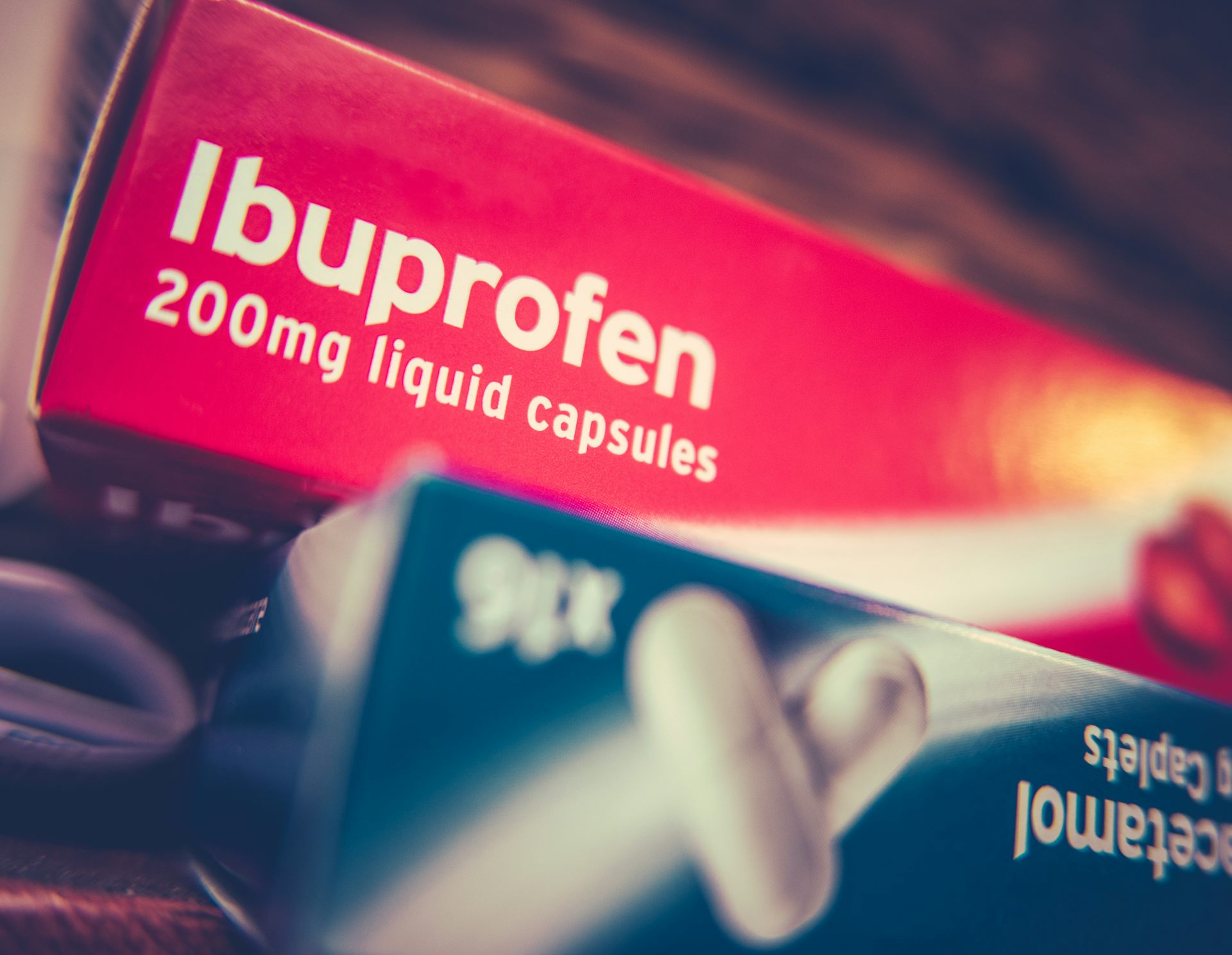 A red box of ibuprofen stacked on top of a blue box of paracetamol.