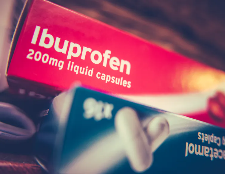 A red box of ibuprofen stacked on top of a blue box of paracetamol.