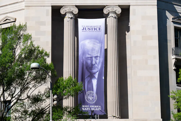 A long banner featuring the face of President Trump hangs on the front of a building.