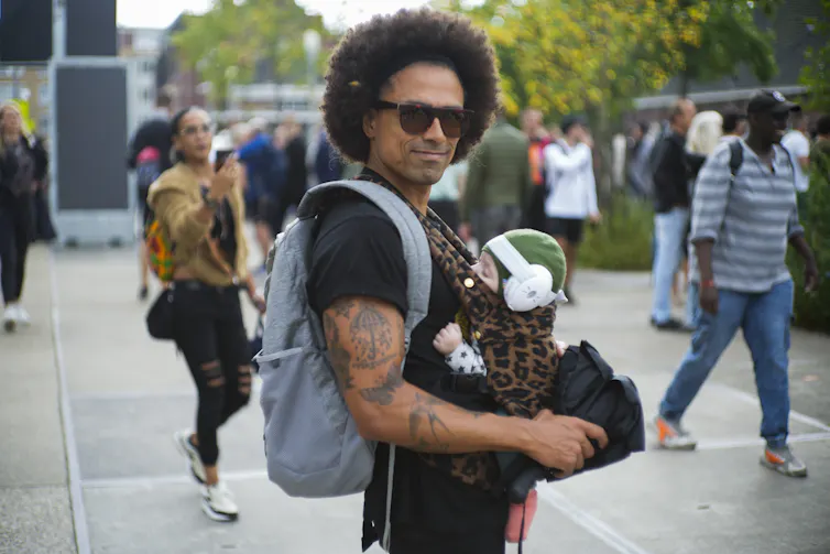 Un homme avec un bébé dans un porte-bébé sur le ventre.
