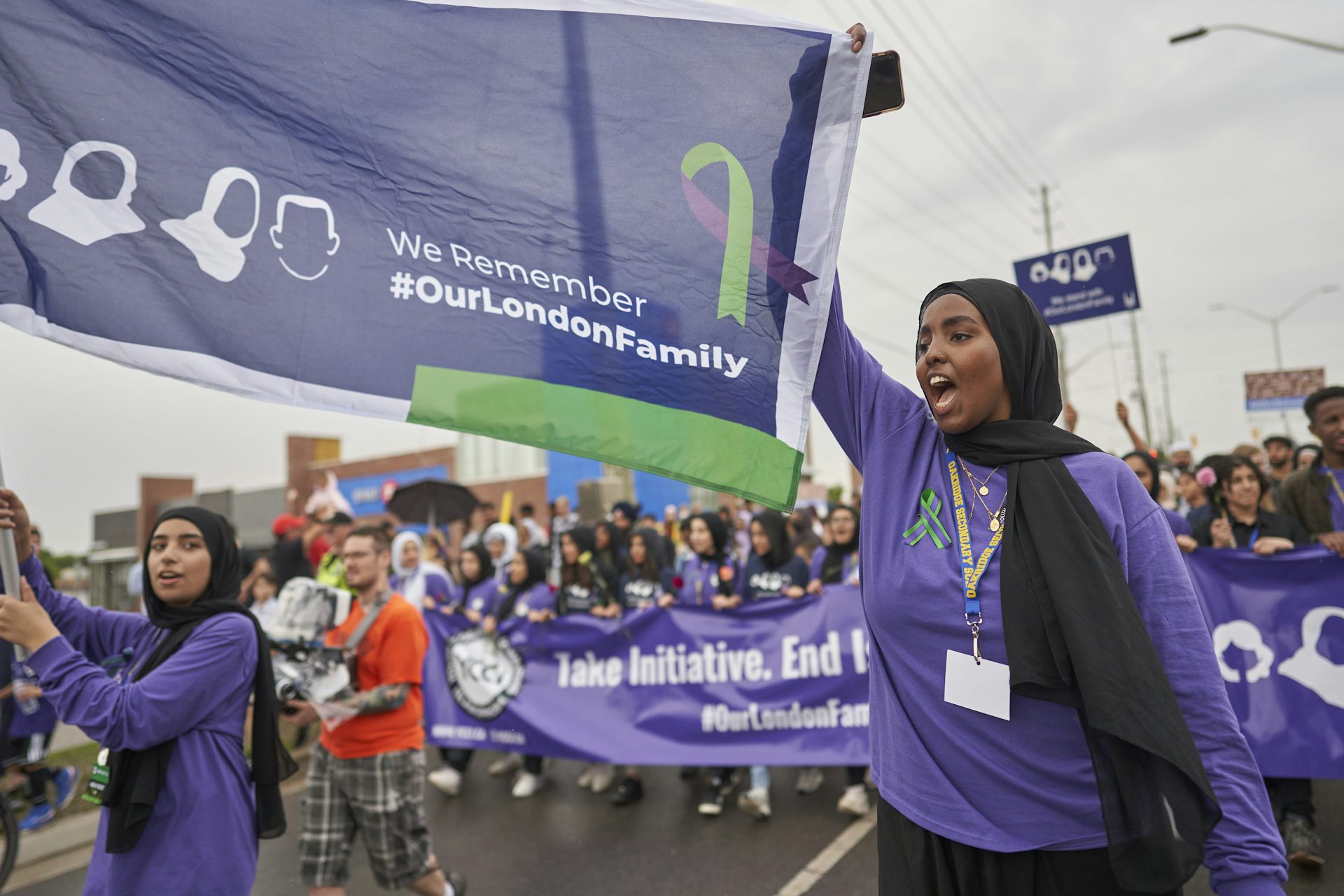 A large crowd of people march carrying a banner that says We Remember Our London Family