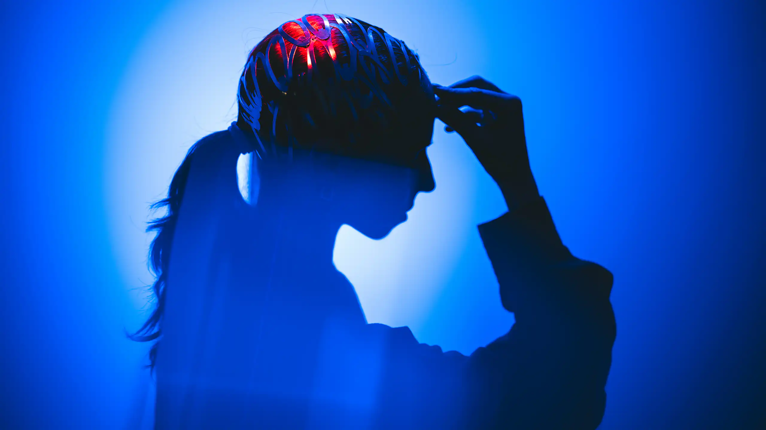 A silhouette of a person surrounded by vibrant abstract light, with parts of the brain lighting up.