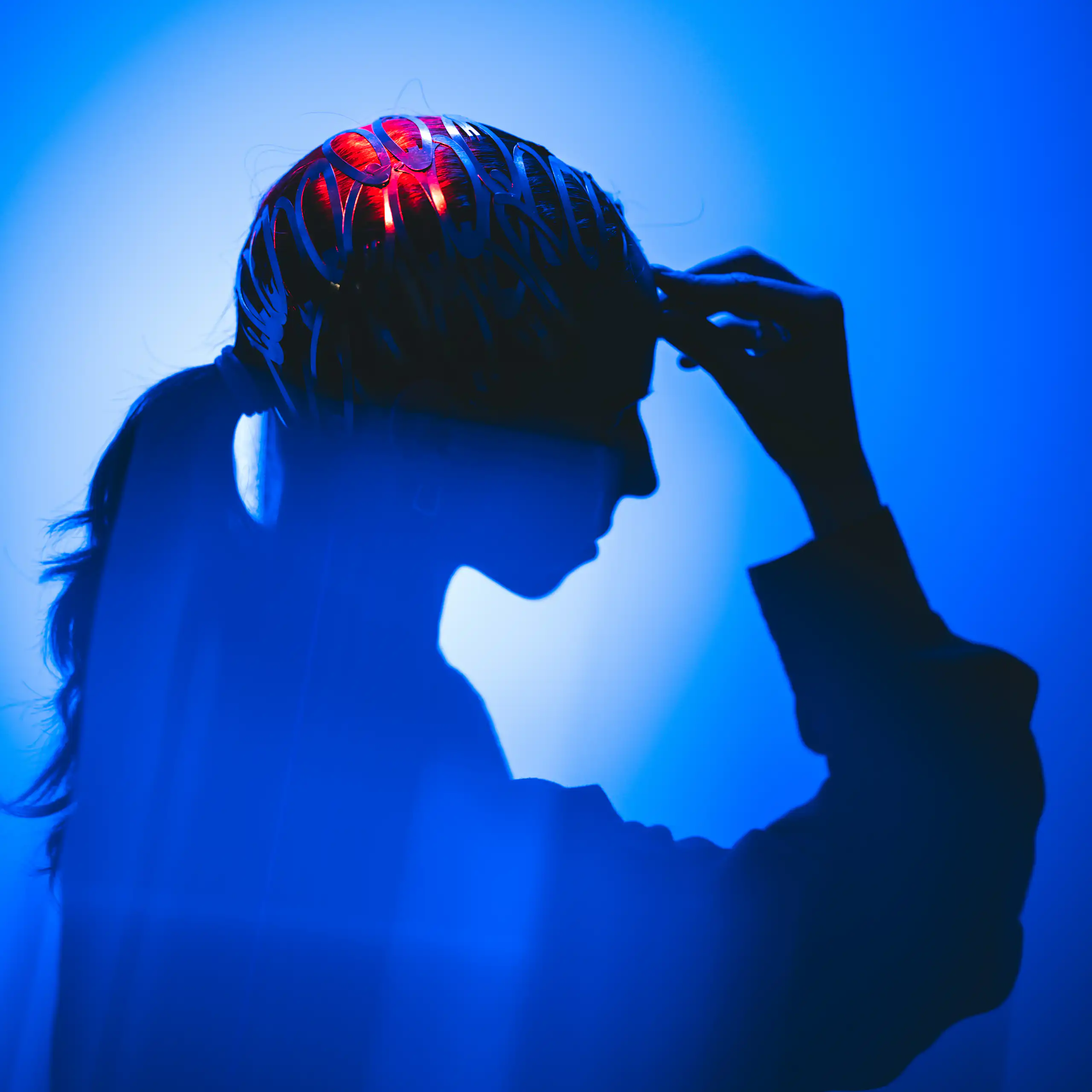 A silhouette of a person surrounded by vibrant abstract light, with parts of the brain lighting up.