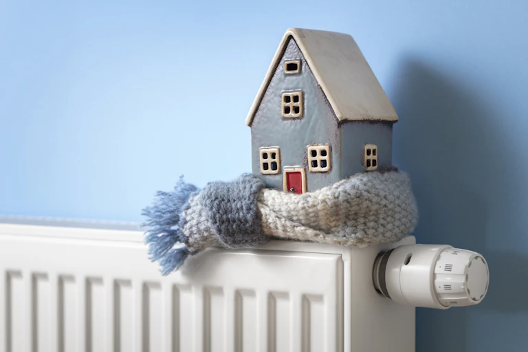 A model house wrapped in a scarf, sitting on a heater.