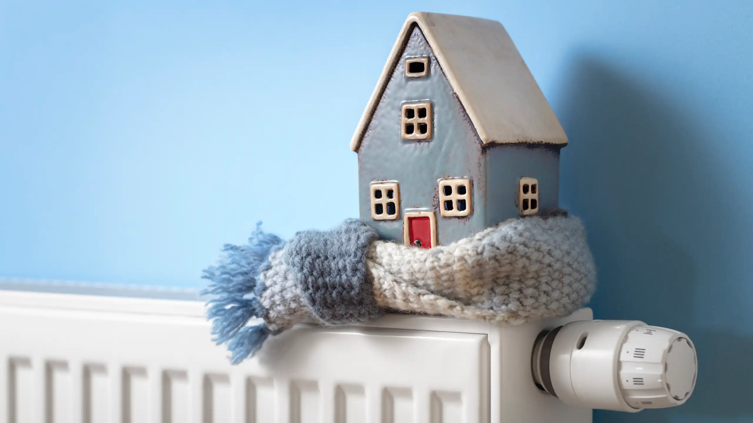 A model house wrapped in a scarf, sitting on a heater.