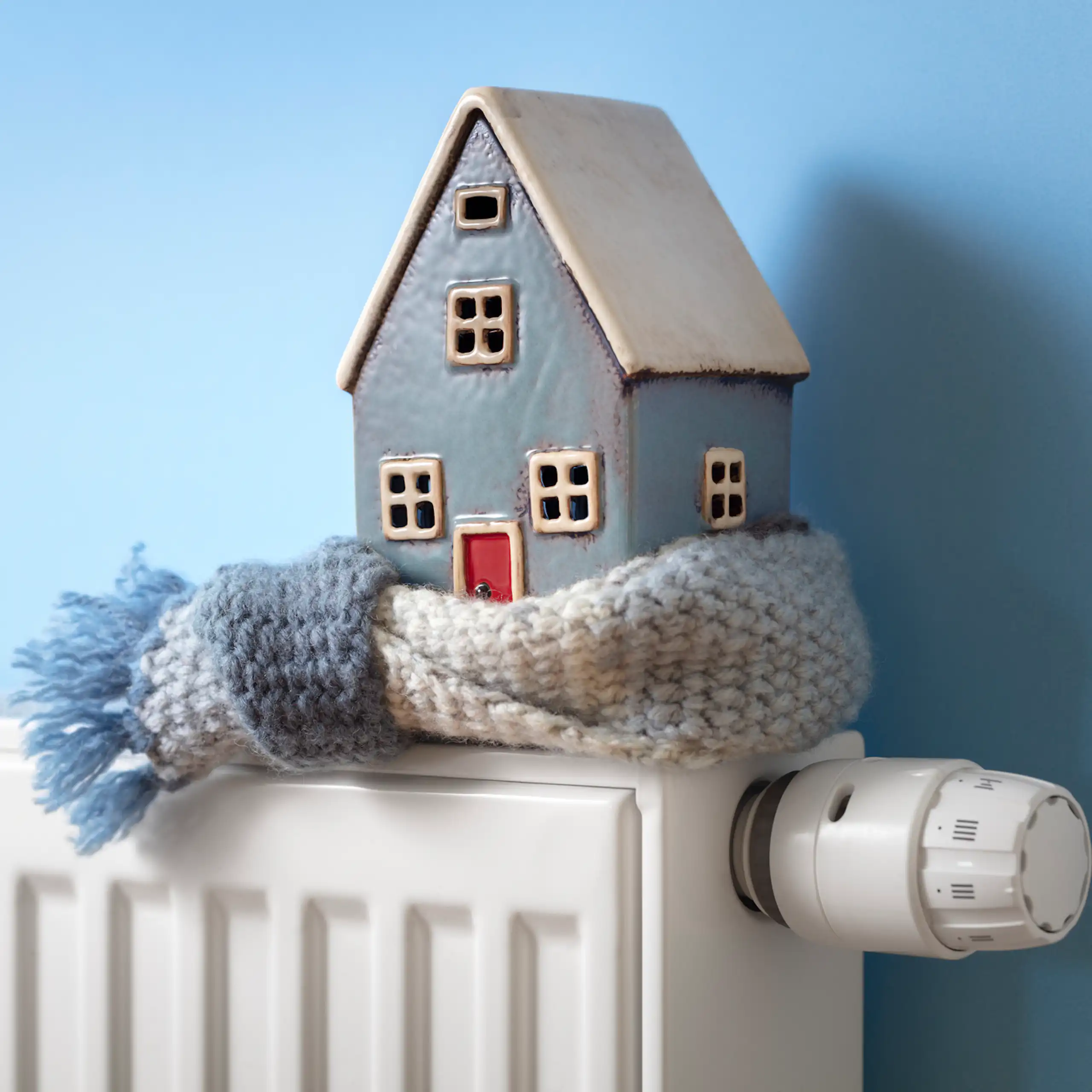 A model house wrapped in a scarf, sitting on a heater.