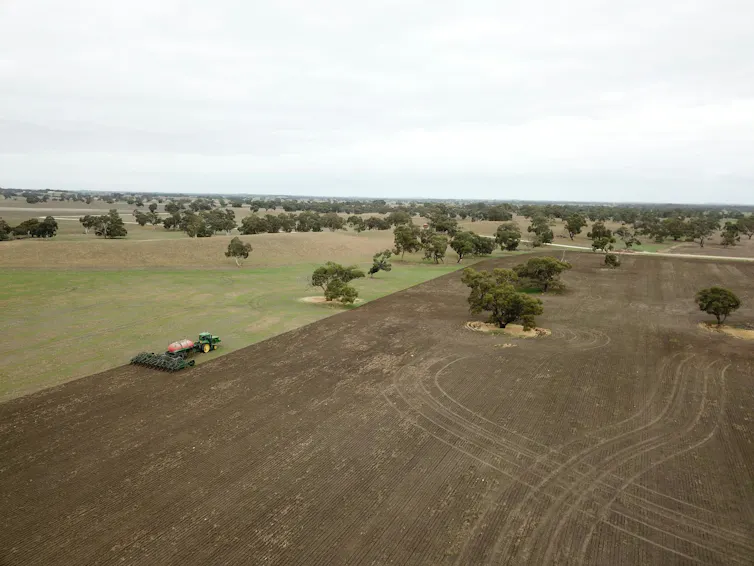aerial view of an Australian farm with tractor tilling soil.