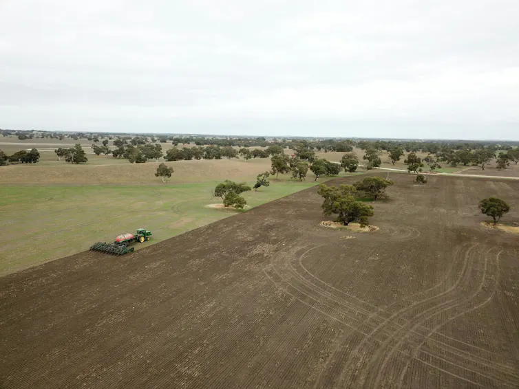 aerial view of an Australian farm with tractor tilling soil.