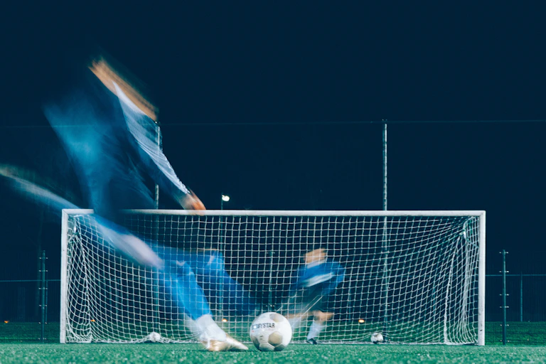 Blurred images of a soccer player and goalkeeper in the moments before a penalty kick