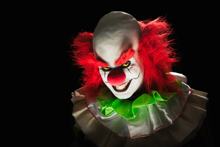 High contrast image of a scary clown on a black background.