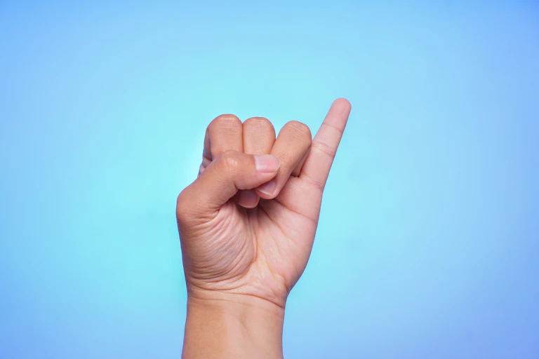 Pinky finger against a blue background.