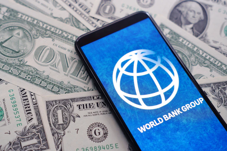Logo de la Banque mondiale sur un tas de dollars.