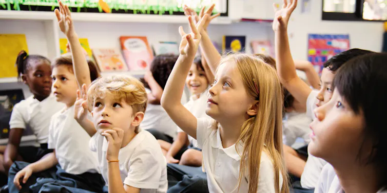 Children in class raising hands