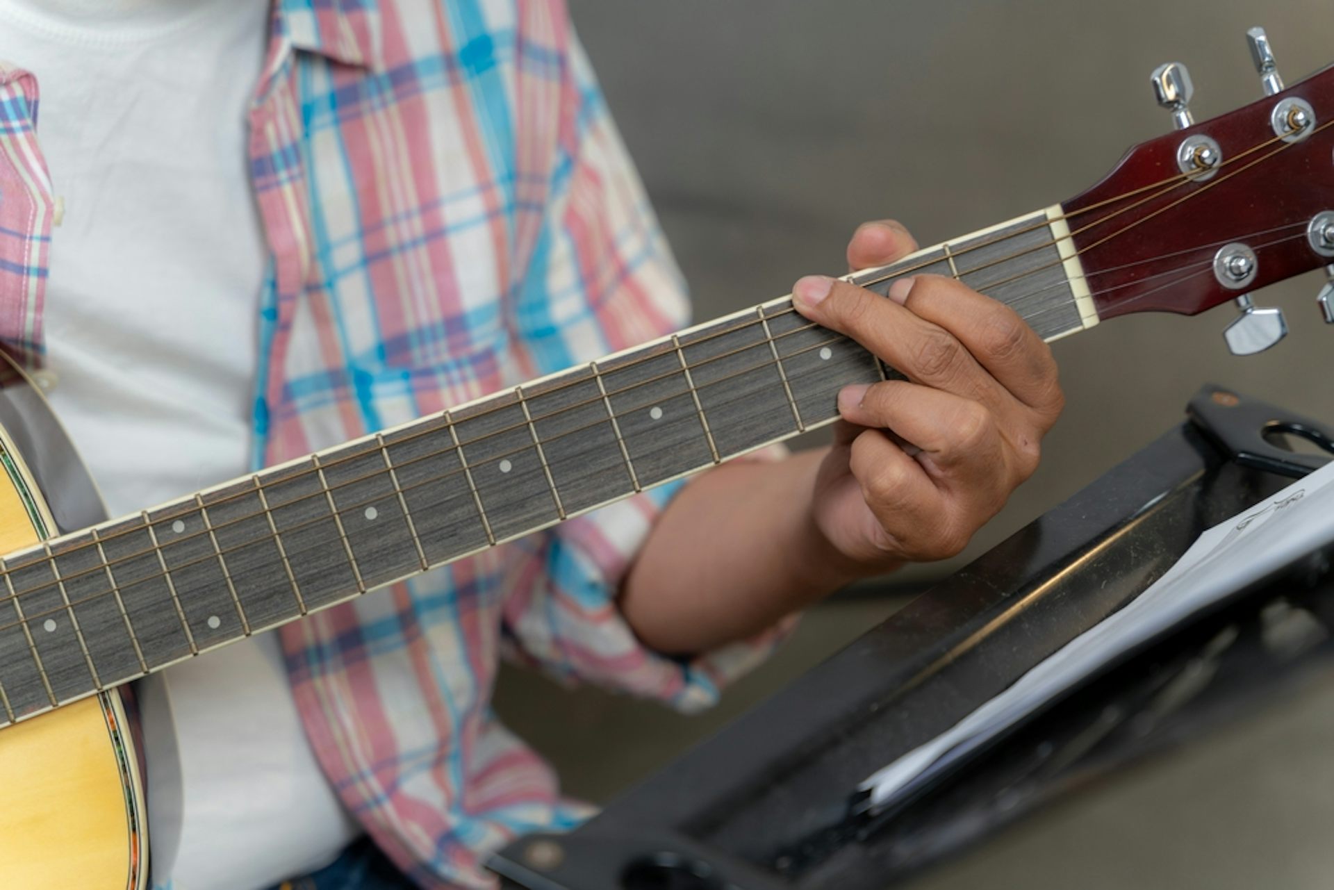 A person forming a chord on a guitar.