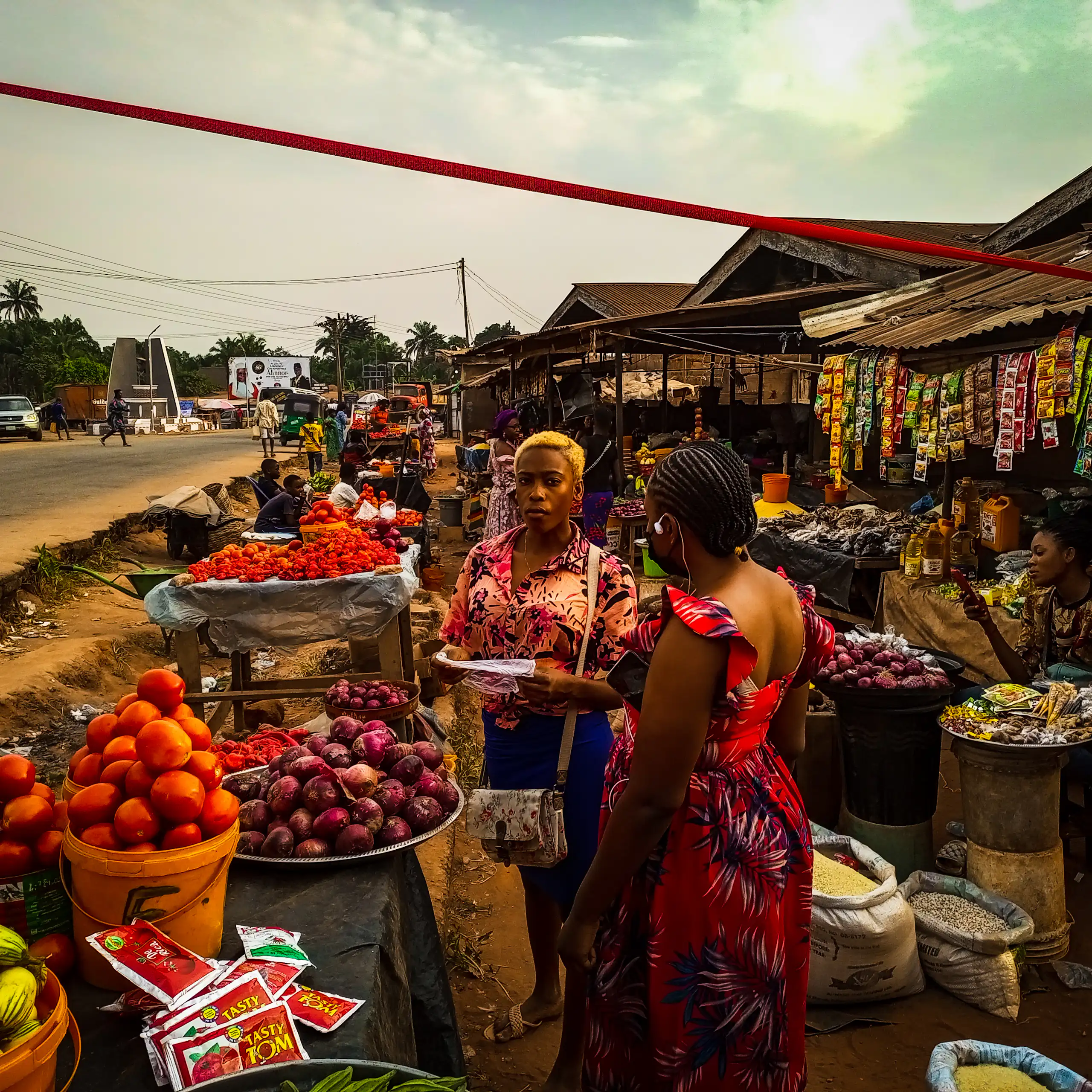 Women at a street market among displays of food items