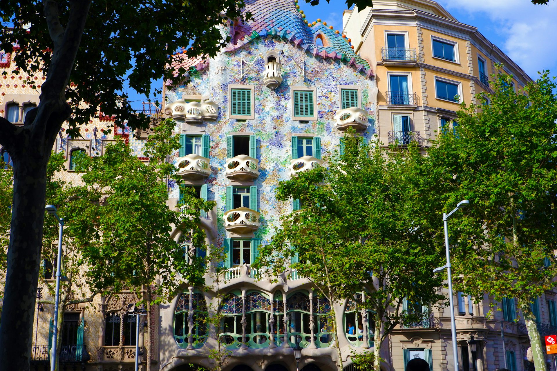 Foto de un edificio residencial en el centro de Barcelona, ​​con azulejos de colores y árboles delante.