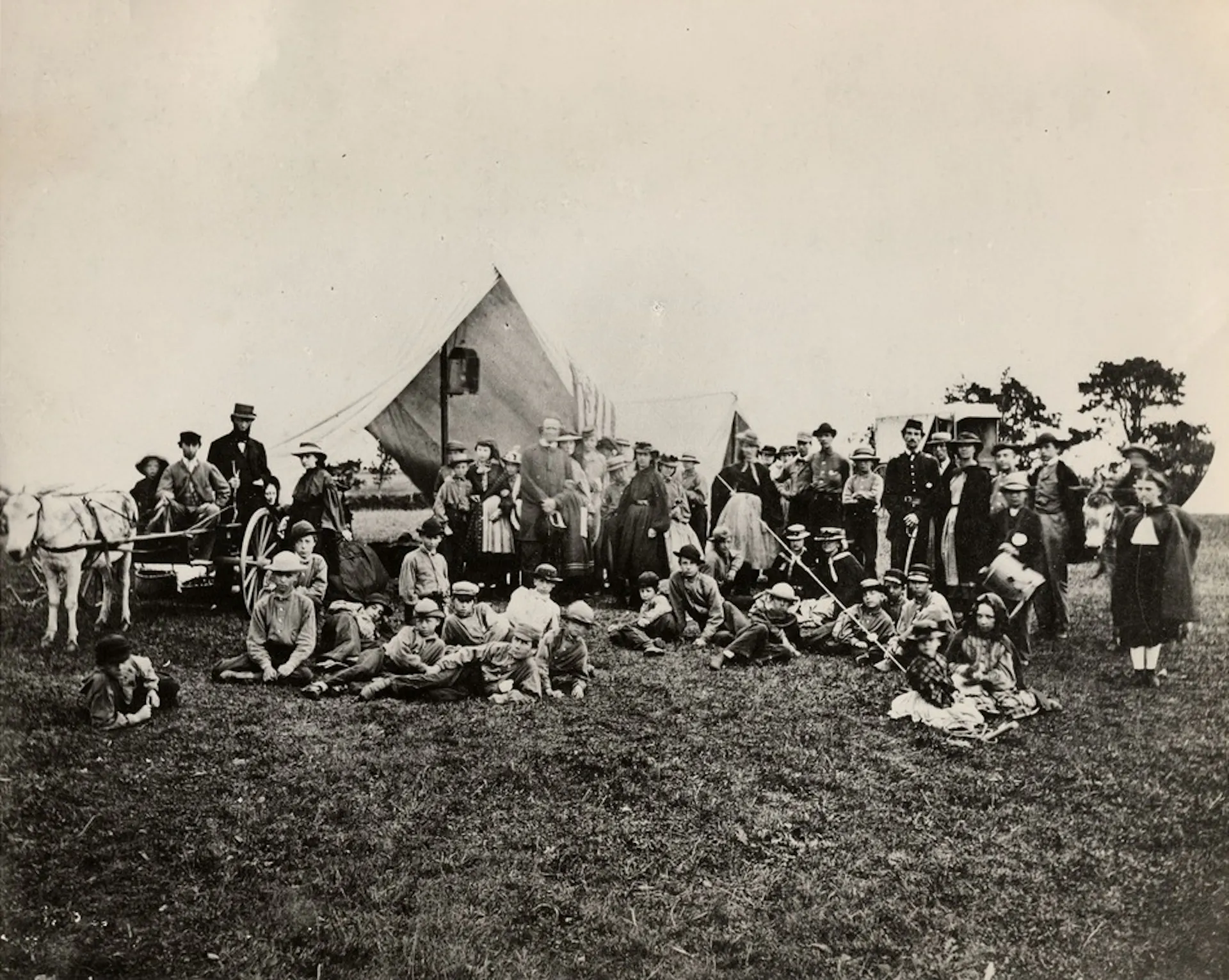 Young boys and men pose for a group photo in front of a canvas fly.