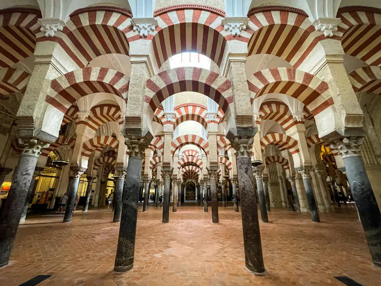 A room with multiple columns and striped red and white archways.