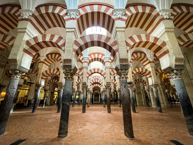 A room with multiple columns and striped red and white archways.