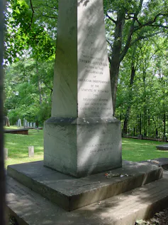 Otra opción revolucionaria de los fundadores de Estados Unidos: la separación de religión y gobierno 3 Un monumento alto y gris se alza sobre una pequeña base en medio de un cementerio rodeado de vegetación.