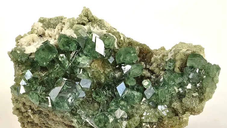 A piece of rock with shiny green crystals embedded.