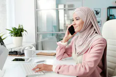No existe una edad "adecuada" para conseguir un trabajo, encontrar pareja o comprar una casa: he aquí por qué parece que sí 1 Una mujer sentada en su escritorio en el trabajo contesta el teléfono y escribe en el teclado de la computadora.