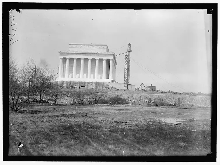 A large, white building with columns, under construction.