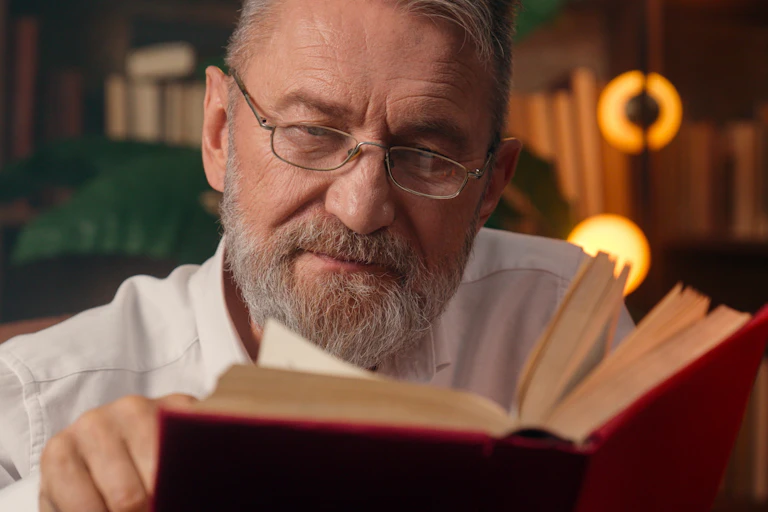 Un hombre con barba cana leyendo un libro