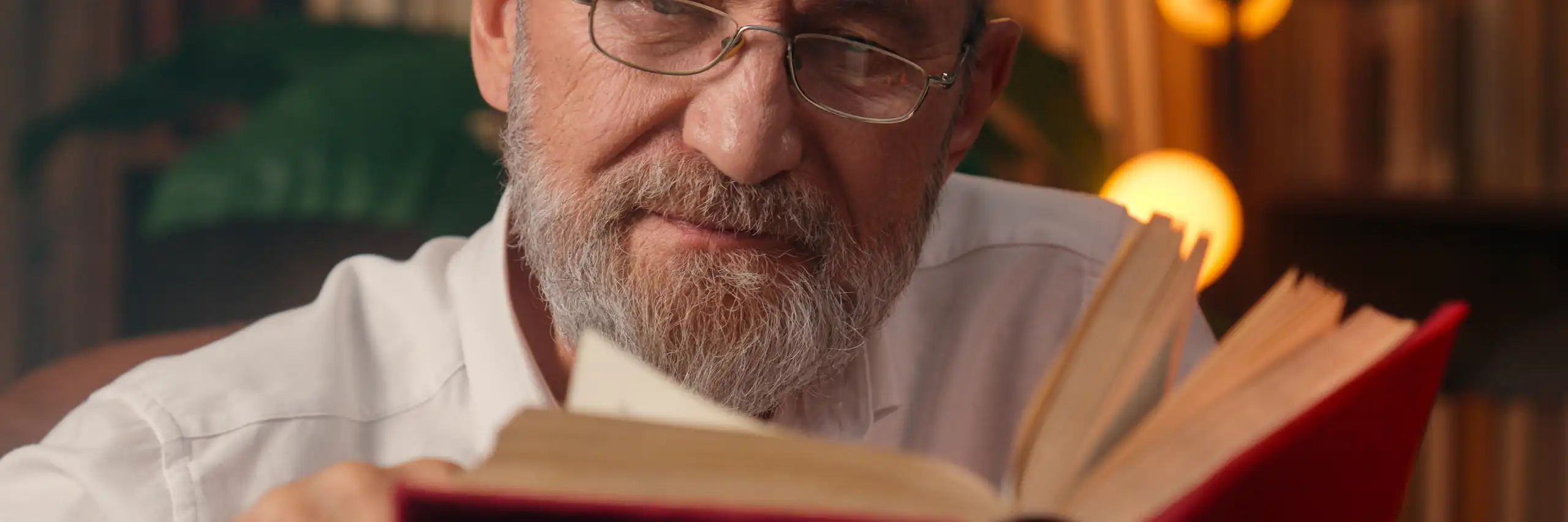 Un hombre con barba cana leyendo un libro