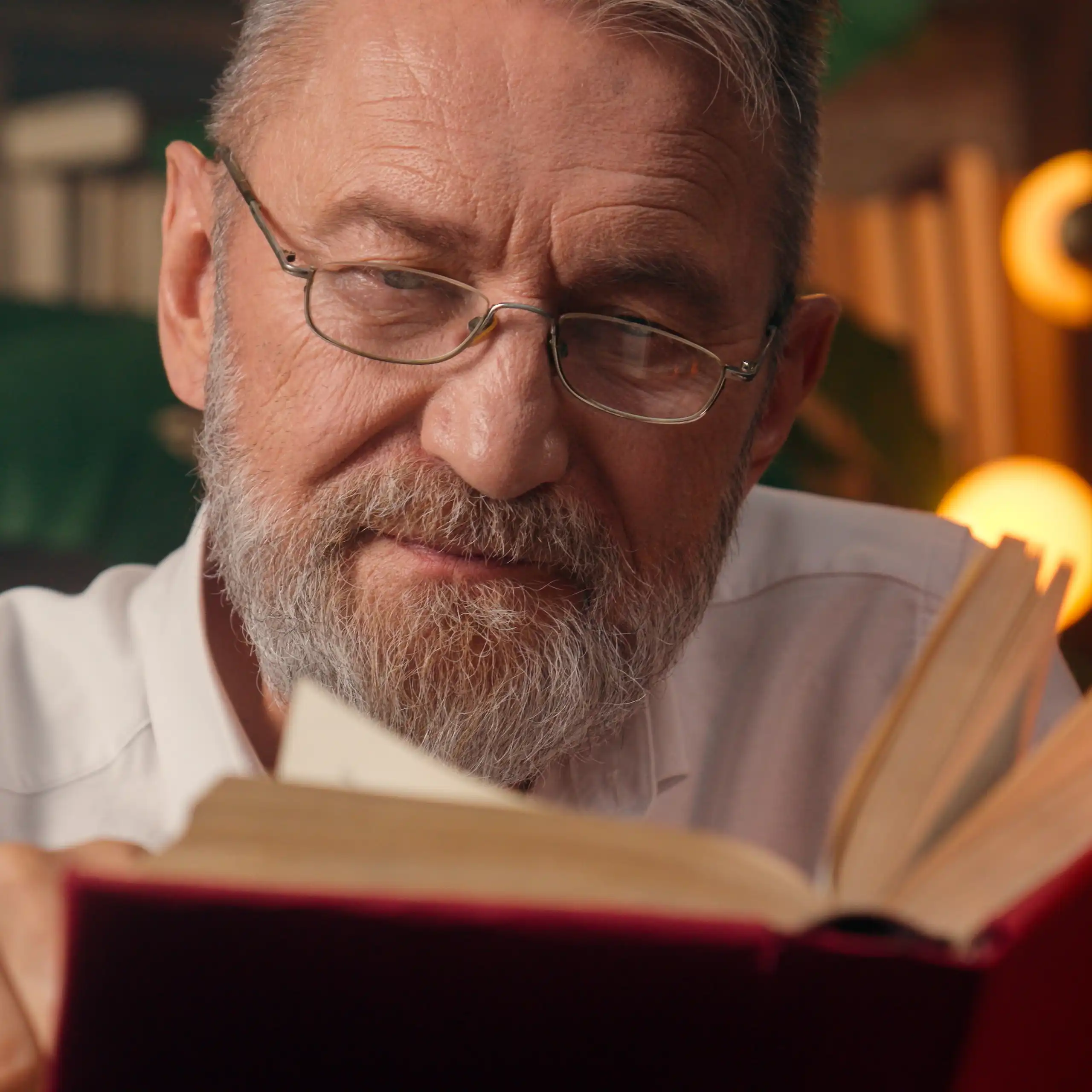 Un hombre con barba cana leyendo un libro