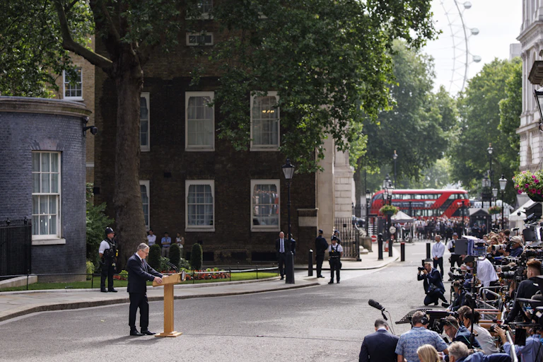 wide view shot of keir starmer at a lectern in downing street delivering his resignation speech in front of assembled media.