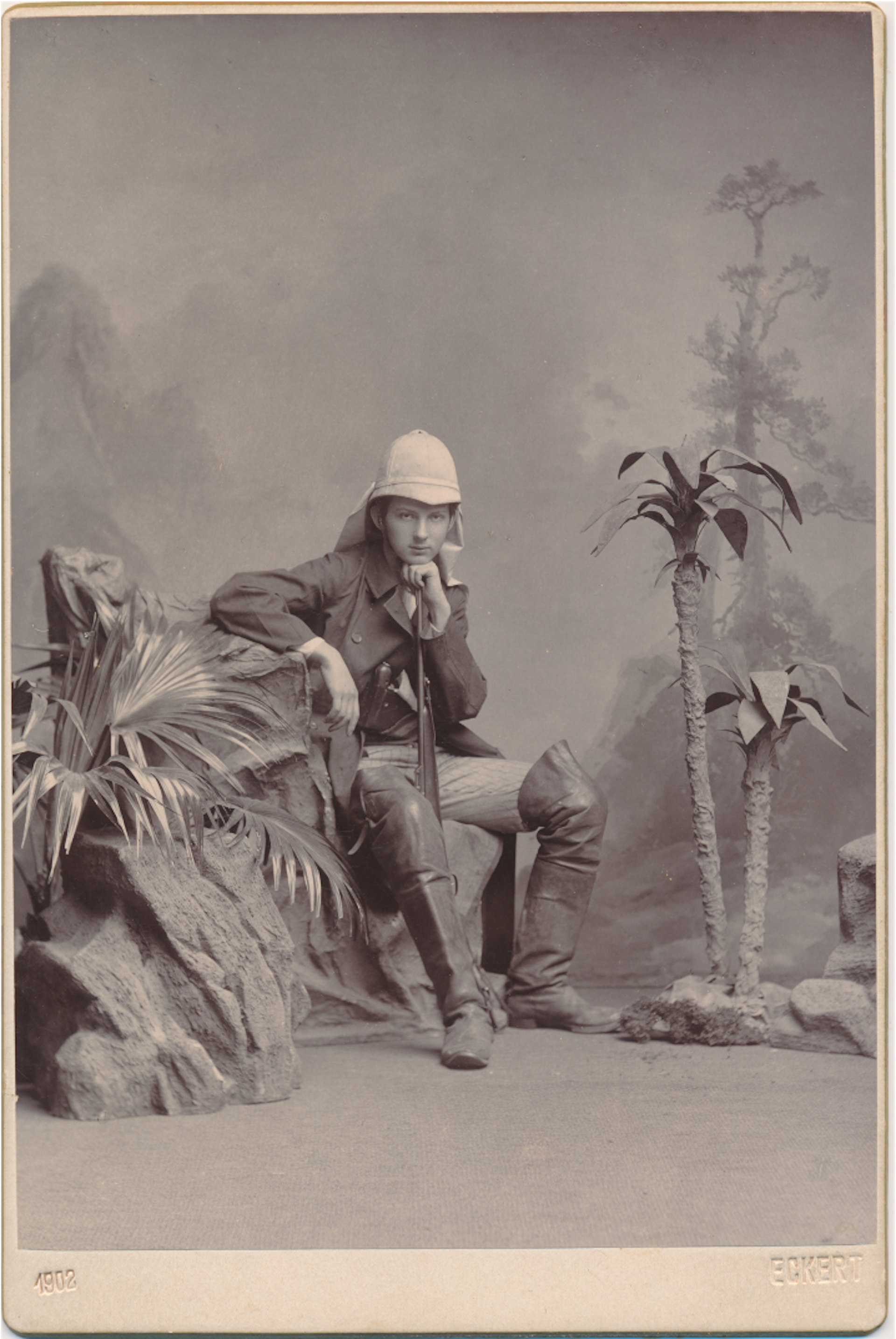Young man poses in studio with plants