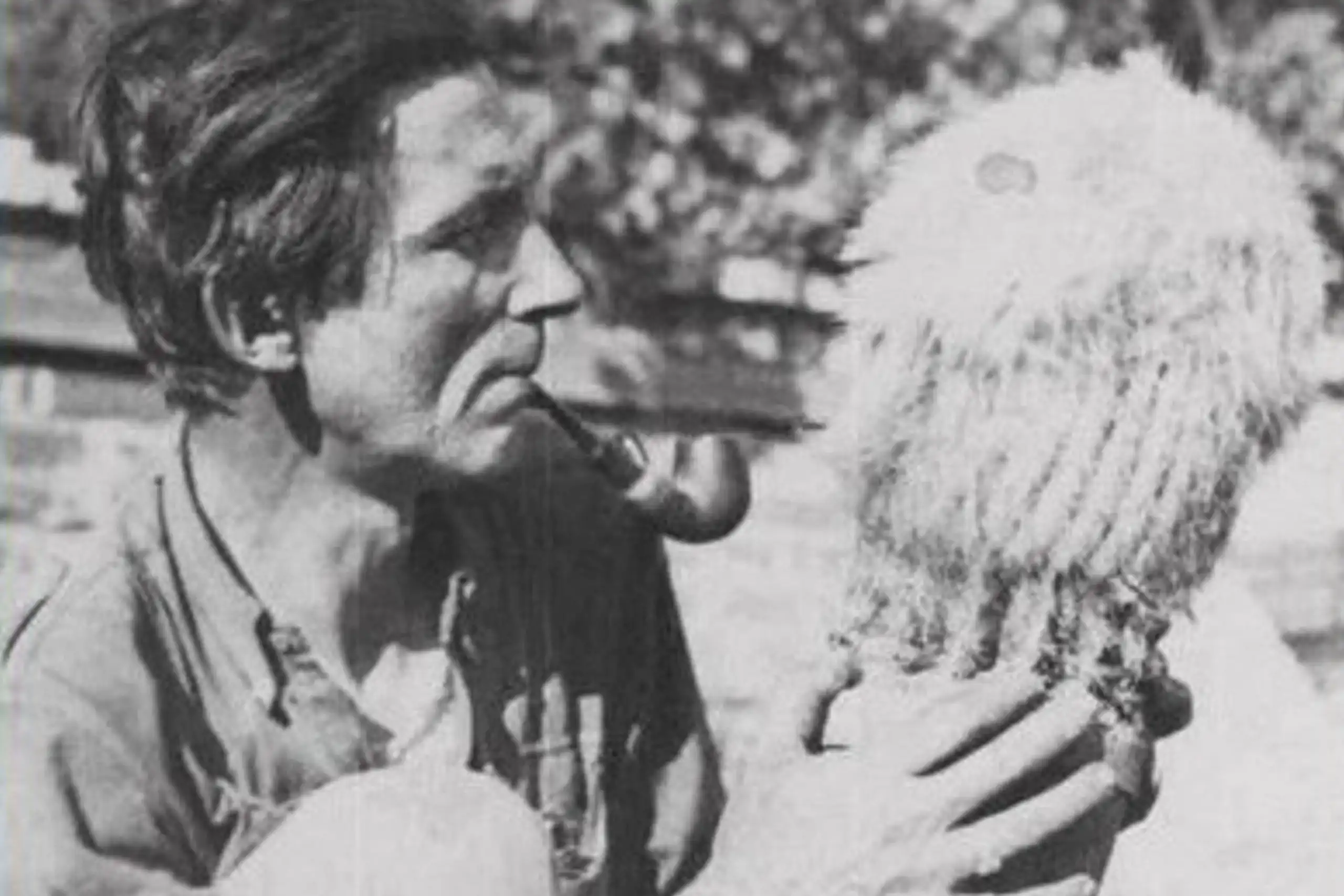 Man looks at cactus while puffing pipe