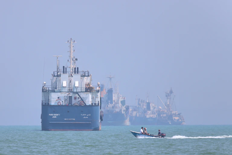 Several ships appear with a motorboat on a stretch of ocean.