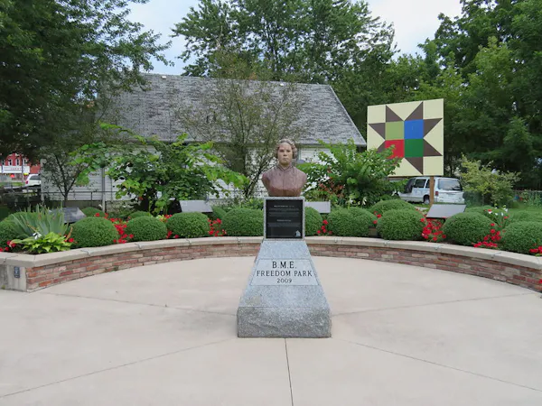 A statue of a woman's face and torso seen in a public square.