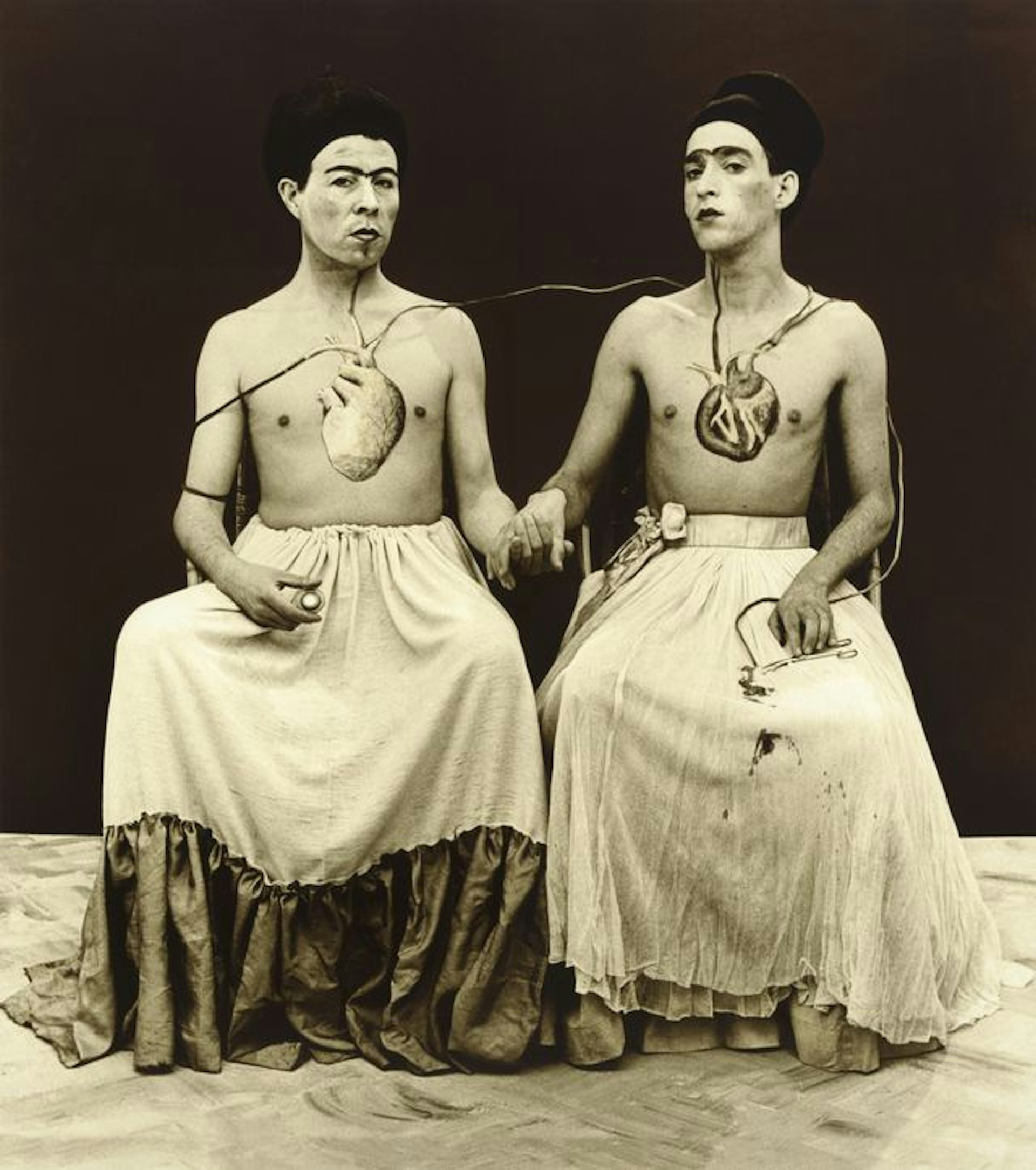 Recreation of a Kahlo painting, two people sat hand in hand.