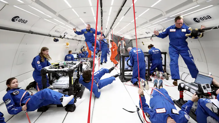 People in blue floating inside aircraft
