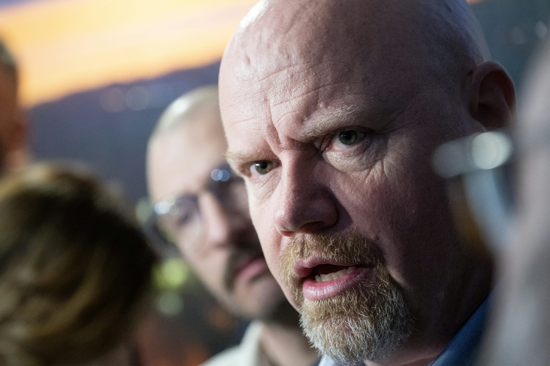 A bald man with a beard speaks.