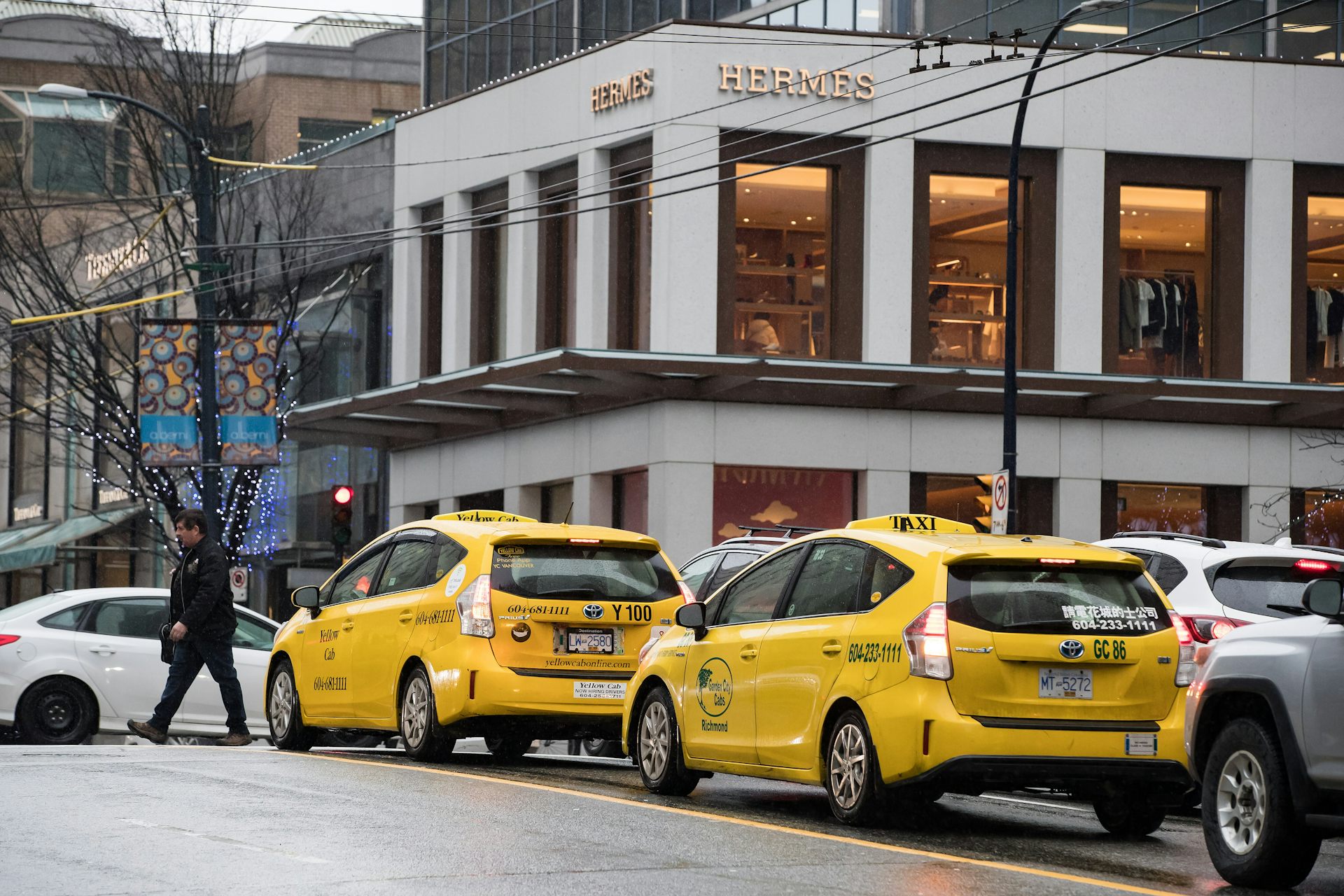 A yellow taxi waits in traffic in front of the Hermes store in downtown Vancouver.